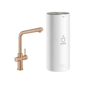 Een moderne Grohe Red 3-in-1 L-uitloop Mat Brons L-vormige boiler keukenkraan met één hendel zit naast een hoge, cilindervormige witte waterfilterunit met de tekst GROHE Red, met symbolen voor glas en heet water.